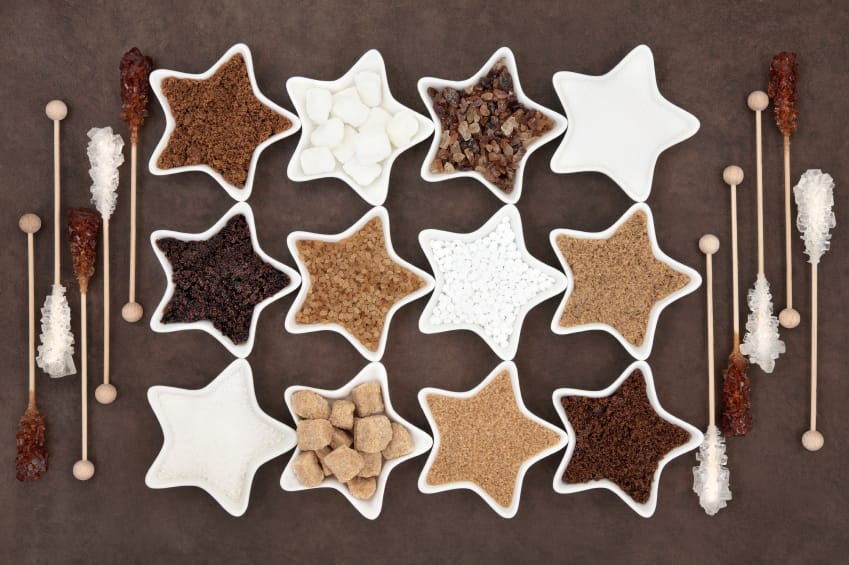 Brown and white sugar selection with crystal lollipops in abstract design over brown paper background.